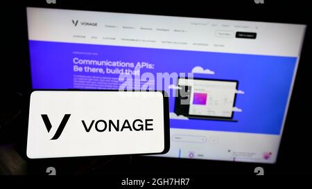 Persona che tiene uno smartphone con il logo della società statunitense di cloud Vonage Holdings Corp. Sullo schermo di fronte al sito web. Mettere a fuoco sul display del telefono. Foto Stock