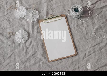 Inverno festivo vita morta. Ornamenti di Natale, decorazione. Fiocchi di neve di carta bianca e corda regalo decorativa su tovaglia di lino beige. Carta bianca Foto Stock