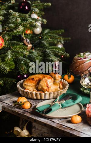 Pollo al forno come il piatto principale delle feste su un tavolo decorato con ghirlanda. Nuovo anno di Natale concetto di festa di famiglia. Foto Stock