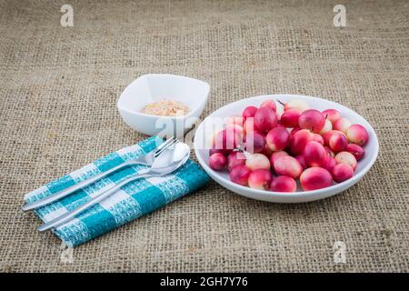 Carunda o Karonda fruttato con cucchiaio e forchetta su fondo di sackcloth Foto Stock