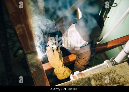 Giovane lavoratore che utilizza la torcia di saldatura mentre lavora in loco Foto Stock