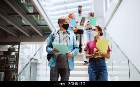 Studenti universitari che camminano lungo le scale e parlano al chiuso, concetto di coronavirus. Foto Stock