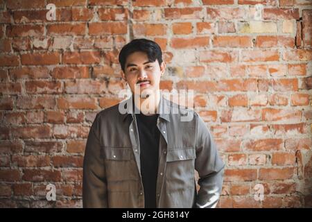 Fiducioso giovane uomo d'affari contro muro di mattoni Foto Stock