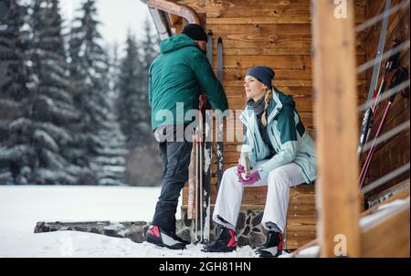 Coppia matura riposante da capanna di legno all'aperto nella natura invernale, sci di fondo. Foto Stock