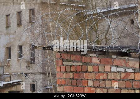 nuovo filo spinato sul tetto di un vecchio edificio vicino ad una zona devastata Foto Stock