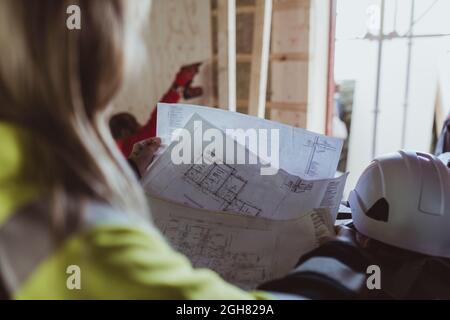 Costruzione femminile lettura piano pavimento durante l'analisi in cantiere Foto Stock