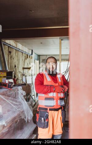 Sorridente lavoratore di costruzione barbuto che lavora in loco Foto Stock