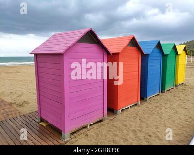 Capanne di legno di vari colori nella sabbia della spiaggia di Oropesa del Mar in una giornata nuvolosa, a Castellón, in Spagna. Europa. Fotografia orizzontale. Foto Stock