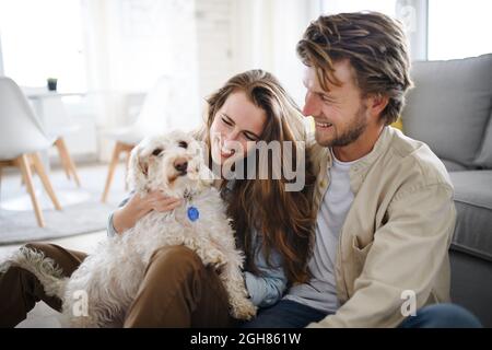 Felice giovane coppia innamorata di cane in casa, riposo. Foto Stock
