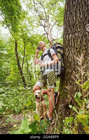 Ragazzo felice che fa chiamata mentre cammina in legno Foto Stock