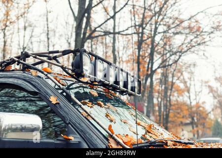 Vista dettagliata della barra del portapacchi realizzata su misura con faro supplementare montato sul tetto della macchina suv pick up per impieghi pesanti contro la nebbia della foresta autunnale Foto Stock