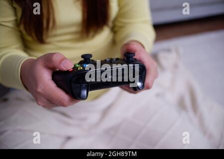 Primo piano le mani della donna che tiene il joystick, giocando i videogiochi nel suo appartamento. Foto Stock