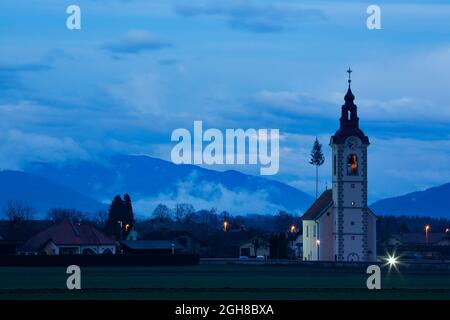 Vista della chiesa di san Simone e Giuda (Sveta Simona in Jude) al crepuscolo come le nuvole si susseguono, Spodnji Brnik, Slovenia. È anche possibile vedere la li Foto Stock