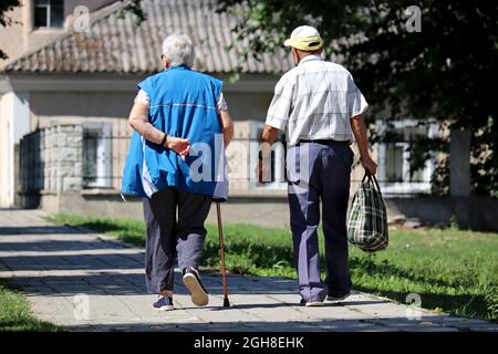 Coppie anziane che camminano su una strada cittadina. Uomo anziano e donna con canna, vita in pensione Foto Stock