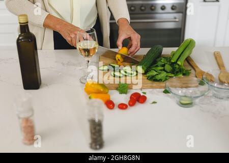 Metà della donna caucasica anziana in cucina moderna, tritare verdure Foto Stock