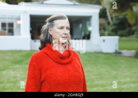 Donna caucasica anziana pensierosa che cammina nel suo giardino Foto Stock