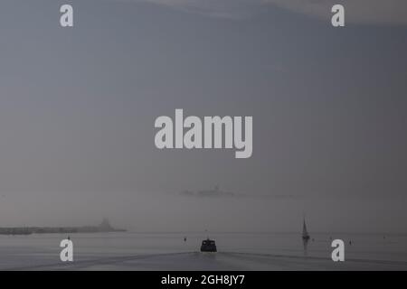 Cardiff, Galles, Regno Unito. 6 settembre 2021. Una barca passeggeri all'ora di pranzo parte dalla baia di Cardiff, dirigendosi verso un Penarth oscurato dalla nebbia durante un periodo di caldo tempo all'inizio di settembre. La torre della chiesa di Sant'Agostino è visibile sul promontorio. Credit: Mark Hawkins/Alamy Live News Foto Stock