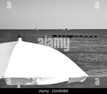 ombrello colorato contro il cielo blu estivo lungo la spiaggia Foto Stock