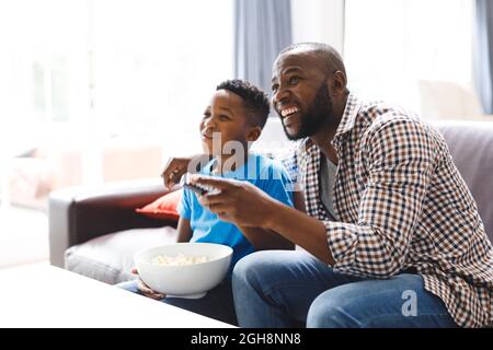 Felice padre e figlio afroamericano seduto sul divano, guardando la tv Foto Stock