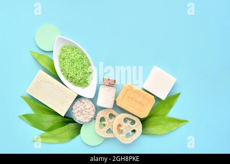 Cosmetici biologici spa - sale da bagno, sapone, spugna e foglie verdi su sfondo blu. Concetto di stile di vita sano. Spazio per il testo Foto Stock