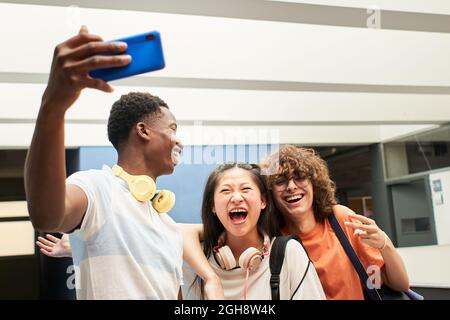 Gruppo multietnico di studenti che prendono un selfie al college. I compagni di classe si divertono insieme. Foto Stock