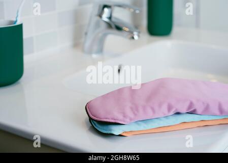 alcuni panni mestruali di diversi colori sul lavello in porcellana bianca di un bagno moderno Foto Stock