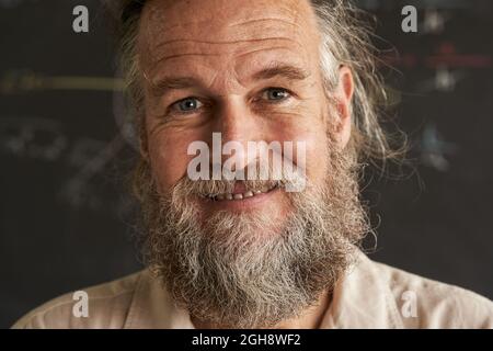 Ritratto di un uomo anziano con barba e capelli grigi. L'uomo ha un sorriso cordiale e sincero. Foto Stock