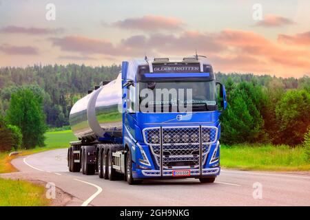 Nuovo, blu Volvo FH540 carro armato di trasporto Sjoman Oy AB su strada al tramonto estivo. Immagine composita. Salo, Finlandia. Giugno 24, 2021. Foto Stock