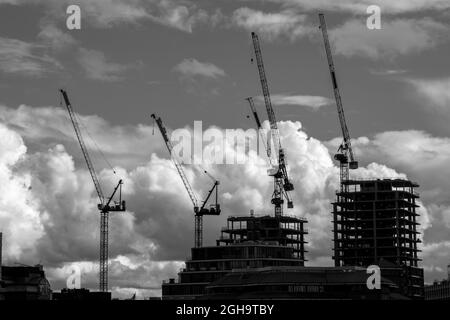 Sagome di gru ed edifici in costruzione nel centro di Londra, in un pomeriggio tempestoso, contro un suggestivo cielo nuvoloso. Foto Stock