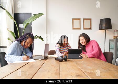 In ufficio. Tre donne d'affari lavorano insieme senza maschere, mantenendo una distanza di sicurezza. Stanno discutendo le questioni di affari. Sul tavolo ci sono Foto Stock