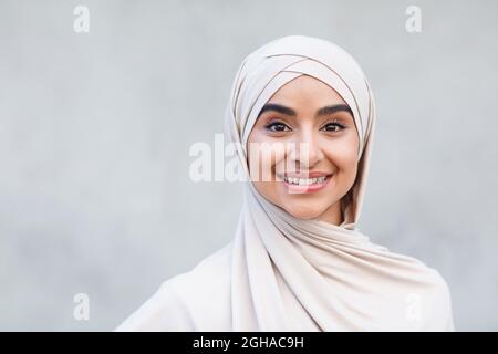 Ritratto di allegro cute attraente giovane arabo islamico femmina in hijab guarda la macchina fotografica Foto Stock