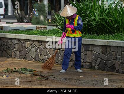 L'operaio municipale spazzava la strada con un bastone. City Street Janitor rende igienico-sanitari. Nha Trang, Vietnam: 2020-10-18. Foto Stock