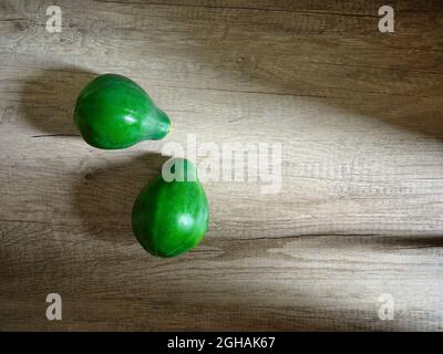 due papaie verdi con sfondo in legno Foto Stock