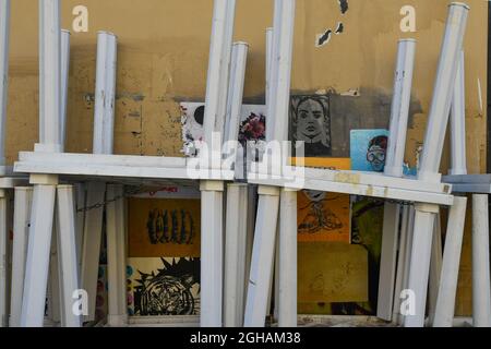 Tavoli impilati su un muro di graffiti con opere di artisti di strada diversi (Blub, Libertà, Ligama, Ache 77) nel quartiere Nuova Venezia, Livorno Foto Stock