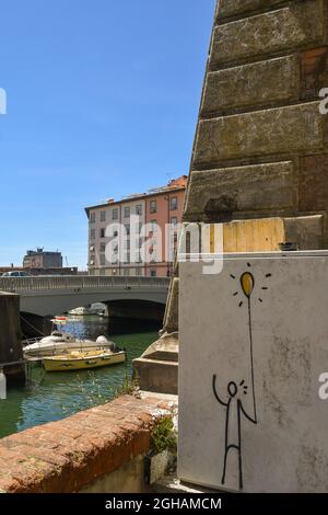 Un contatore di gas con il graffito 'il piccolo uomo' dall'uscita Entra affacciato su un canale della Nuova Venezia, Livorno, Toscana, Italia Foto Stock