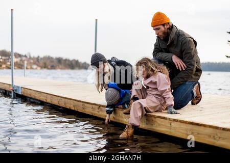 Uomo e donna con figlio e figlia sul molo al lago Foto Stock