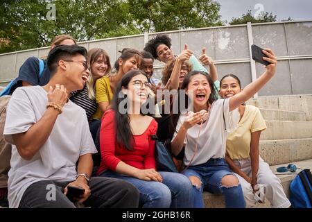 Gruppo di studenti multirazziali che prendono selfie con il cellulare. Compagni di classe che si divertono insieme. Foto Stock
