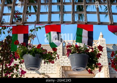 Decorazioni della bandiera nazionale degli Emirati Arabi Uniti appese tra i fiori, Giornata nazionale degli Emirati Arabi Uniti, Dubai. Foto Stock