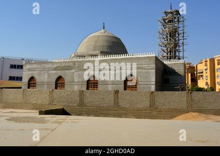 Una nuova moschea in costruzione contro il cielo azzurro soleggiato con il minareto moschea circondato da impalcature di legno e la cupola Foto Stock