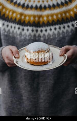 Ragazzo che tiene la semola della pasticceria svedese, su un piatto Foto Stock