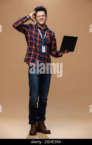 Giovane uomo in possesso di un computer portatile Foto Stock
