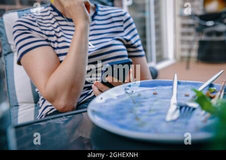 Una donna controlla il suo smartphone iphone al tavolo da pranzo fuori a Londra, Inghilterra Foto Stock