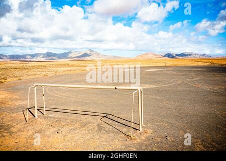 Campo di calcio vuoto nel paesaggio secco circondato da montagne, Fuerteventura, Isole Canarie, Spagna Foto Stock