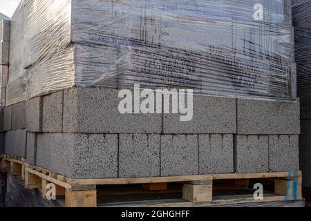 Blocchi di calcestruzzo in schiuma ricoperti di pellicola di imballaggio su pallet in legno nel magazzino Foto Stock