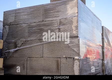 Blocchi di calcestruzzo in schiuma ricoperti di pellicola di imballaggio su pallet in legno nel magazzino Foto Stock