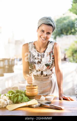 Giovane donna cucina sana cucina mediterranea all'aperto. Stile di vita concetto Foto Stock