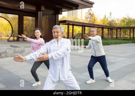 Adulto allegro che pratica Tai Chi nel parco Foto Stock