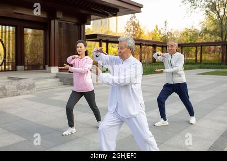 Adulto allegro che pratica Tai Chi nel parco Foto Stock