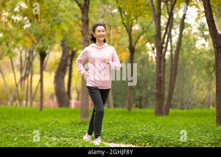 Donna anziana felice che corre nel parco Foto Stock