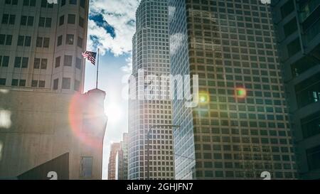 Bandiera americana su un palo tra grattacieli in controluce con lente flare, Los Angeles, California, USA Foto Stock
